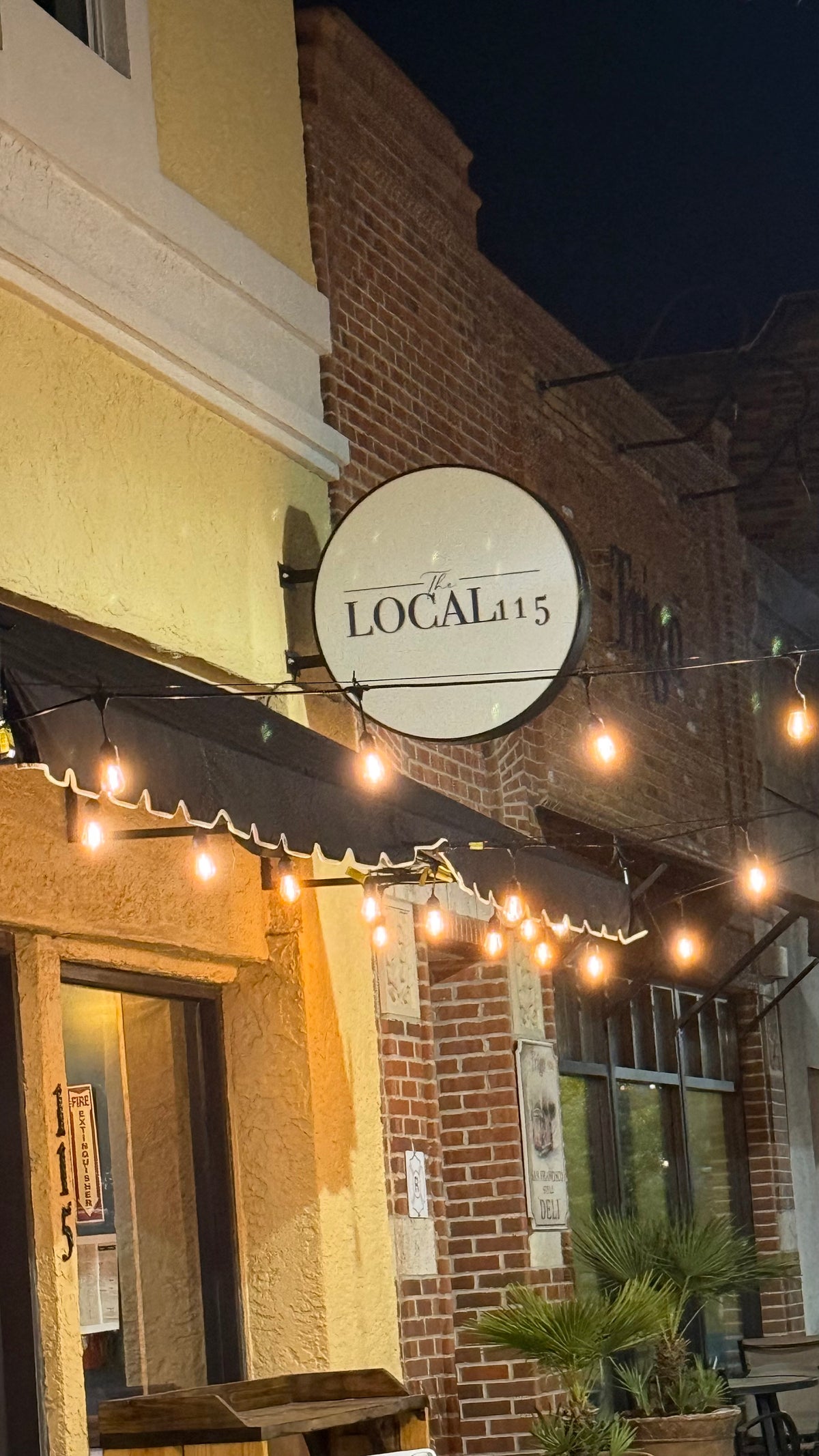 LOCAL 115: round blade sign at dusk