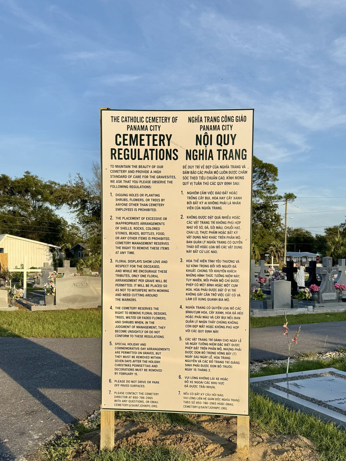 Bilingual cemetery regulations ACM sign installed on wooden posts in Panama City