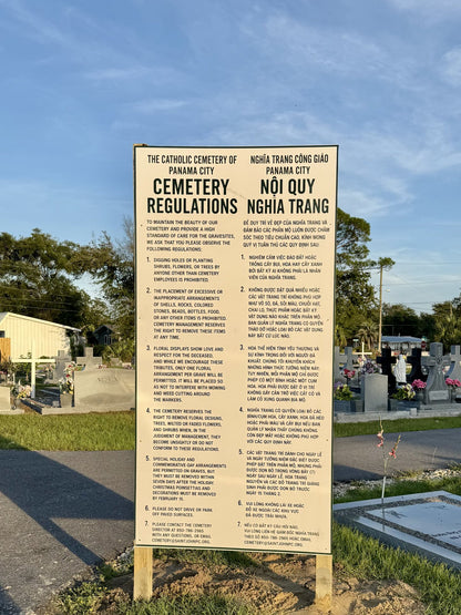 Bilingual cemetery regulations ACM sign installed on wooden posts in Panama City
